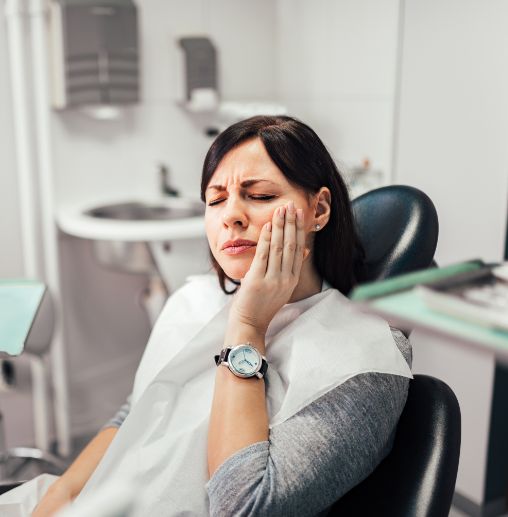 Dental patient holding her cheek in pain