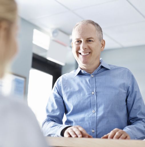 Man smiling at dental office receptionist