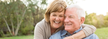 Senior man and woman embracing each other outdoors