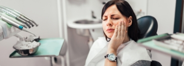 Dental patient holding her cheek in pain