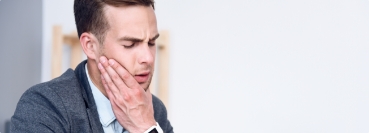 Man holding the side of his jaw in pain