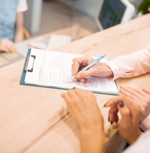 Dental patient signing a form on a clipboard