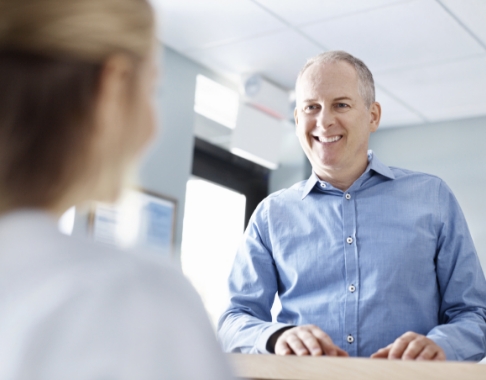 Man smiling at dental office receptionist