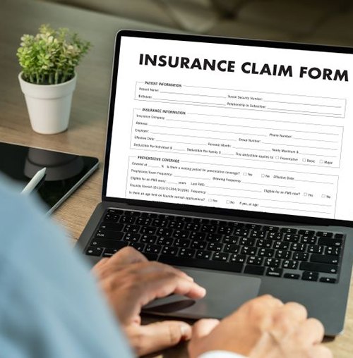 Person using laptop to fill out insurance claim form