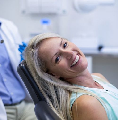 Happy dental patient leaning back in treatment chair
