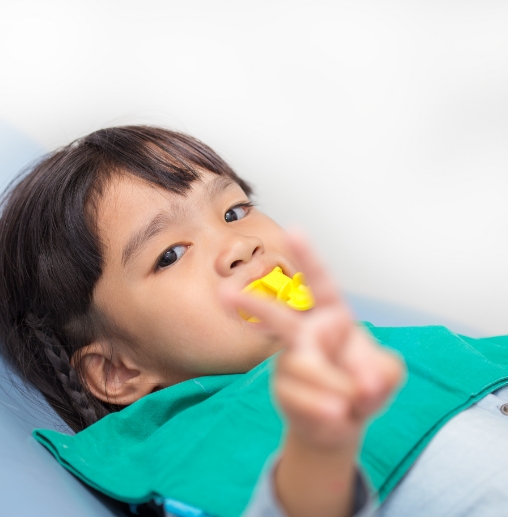 Young girl in dental chair with fluoride trays on her teeth