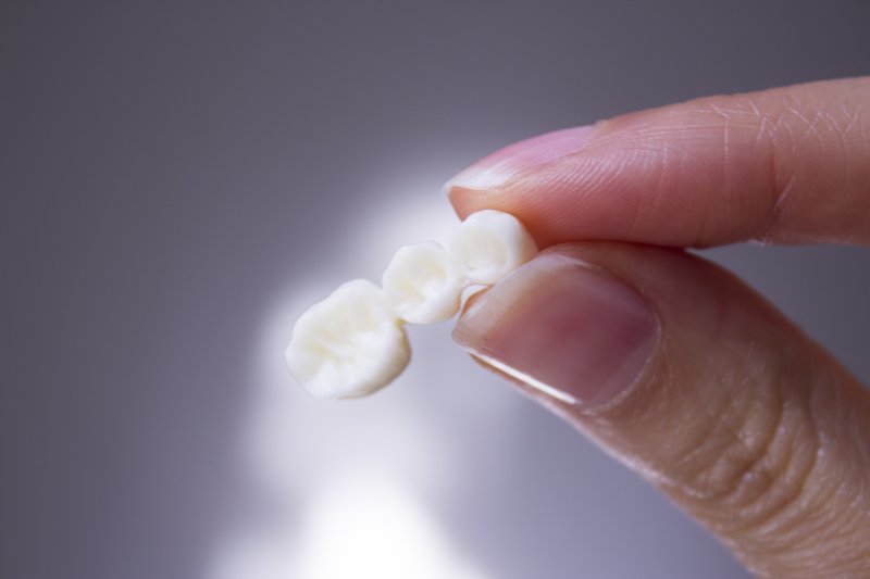 fingers holding a dental bridge