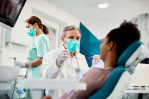 Dentist talking to patient in dentist's chair.