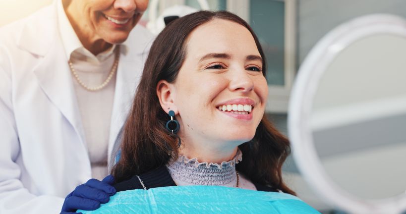 A woman looking in the mirror at her newly improved smile